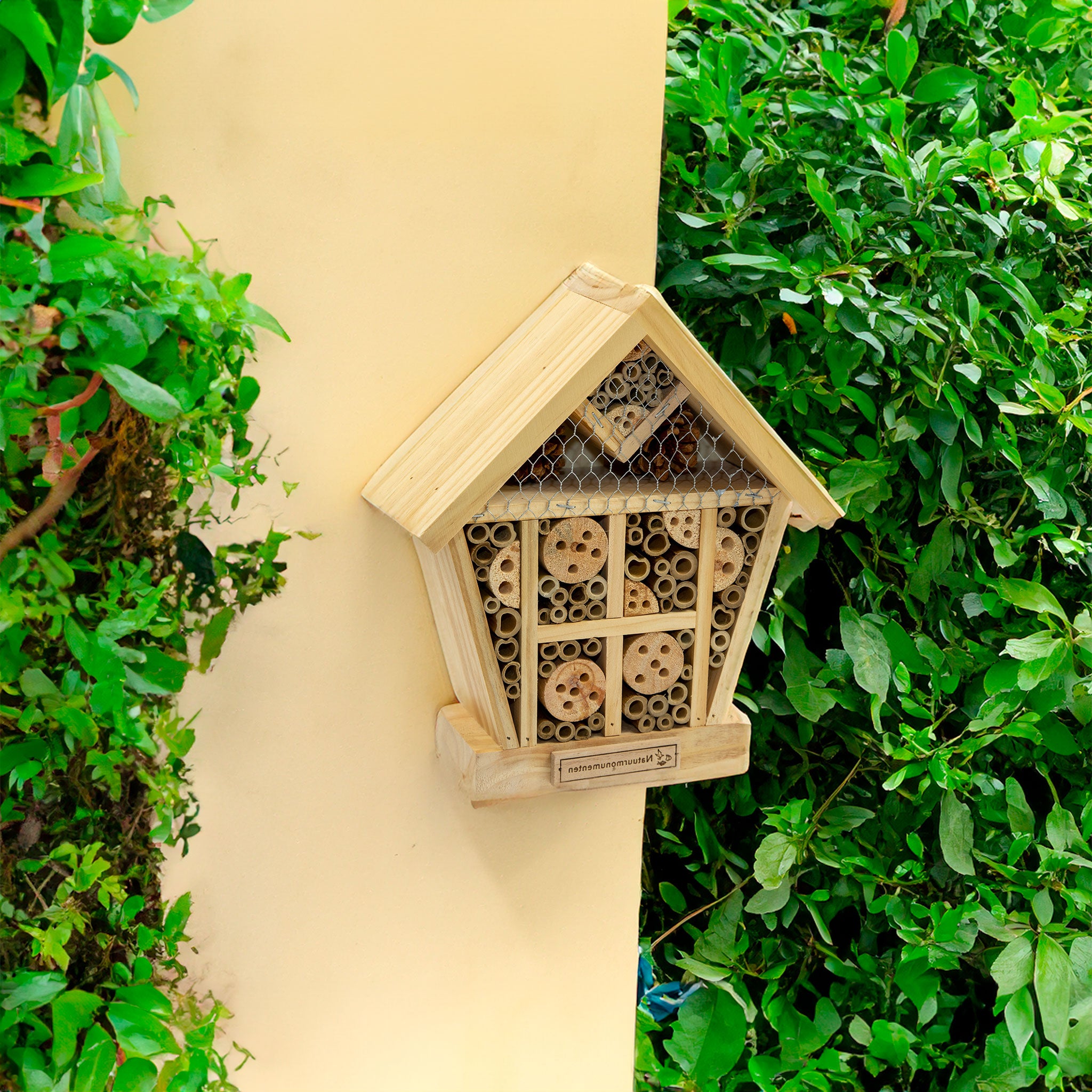 Beneficial Insect Habitat attached to a cream garden wall with bushes surrounding